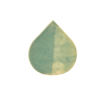 Teardrop-shaped ceramic tile with green and beige pattern on a white background